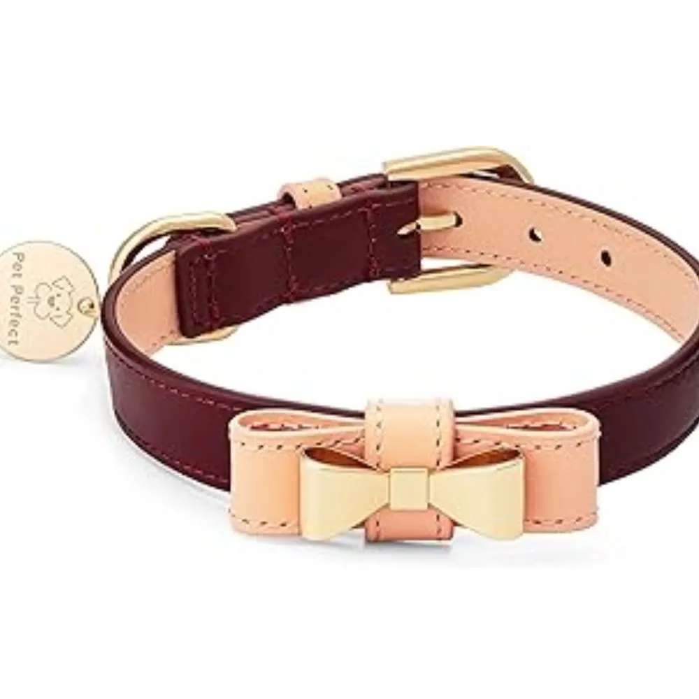 Burgundy leather dog collar with pink leather bow tie accent, gold hardware, adjustable buckle, and circular name tag on white background